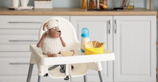 High chair in a kitchen with a stuffed toy, a baby bottle, and a bowl of snacks, representing a baby-friendly and safe space.